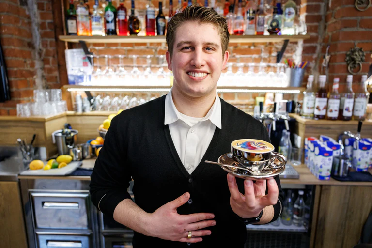 Ihm kann es nicht zu bunt sein: Bozzato bereitet den kunstvollen Milchschaum im Kaffee im Familienbetrieb zu. — © Daniel Karmann/dpa