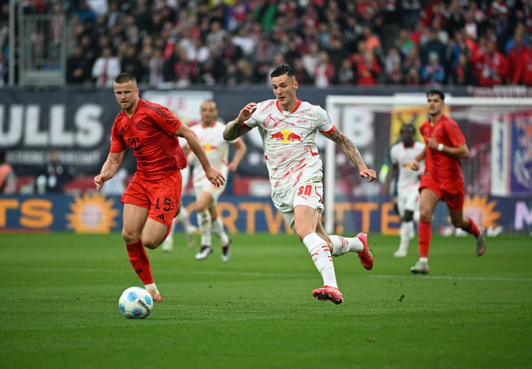 Bayern-Verteidiger Eric Dier (l) im Duell mit Benjamin Sesko. — © Elisa Schu/dpa