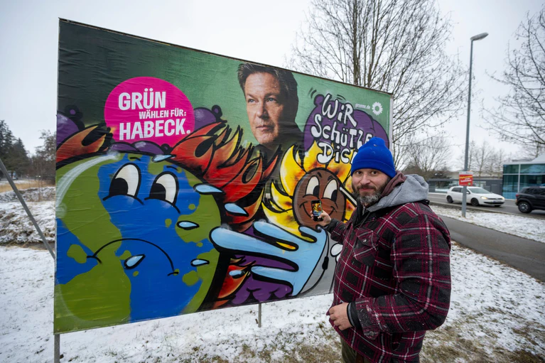 Im Auftrag der Grünen gestaltet der Künstler Bernd Imminger beschädigte Wahlplakate neu. — © Stefan Puchner/dpa