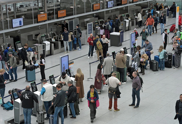 Reisegäste stehen an Check-In-Schaltern am Flughafen. — © Malin Wunderlich/dpa