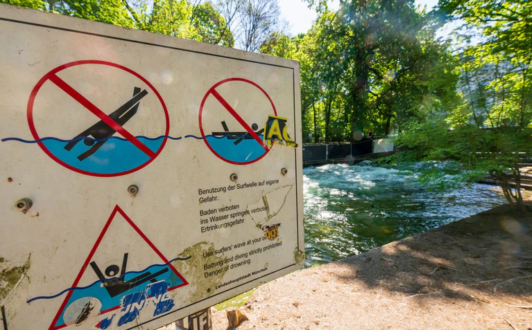 Schilder warnen vor den Gefahren am Eisbach. — © Peter Kneffel/dpa