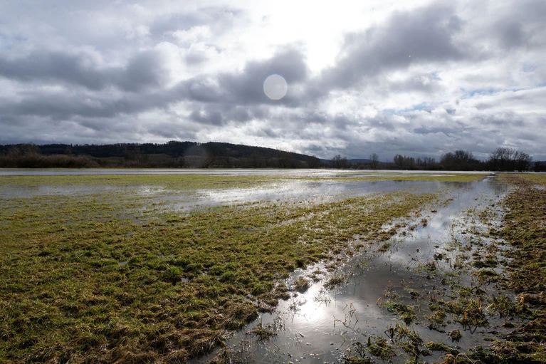 Ein Feld steht unter Wasser, nachdem es in Nordbayern viel geregnet hat und der Schnee weggetaut ist. — © Pia Bayer/dpa